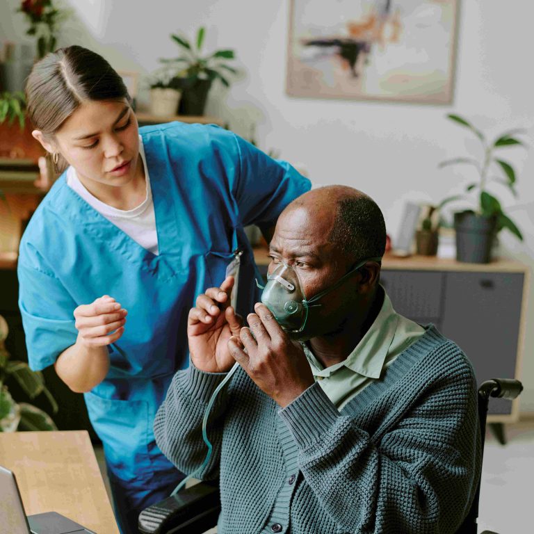 Healthcare professional assisting black elderly man with oxygen mask, scene showing interaction and care in well-lit room with plants and medical equipment